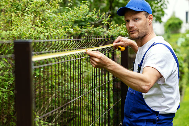 fencing services. worker taking measurements with measuring tape
